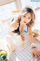 A woman sitting at a table with a bowl of fruit.